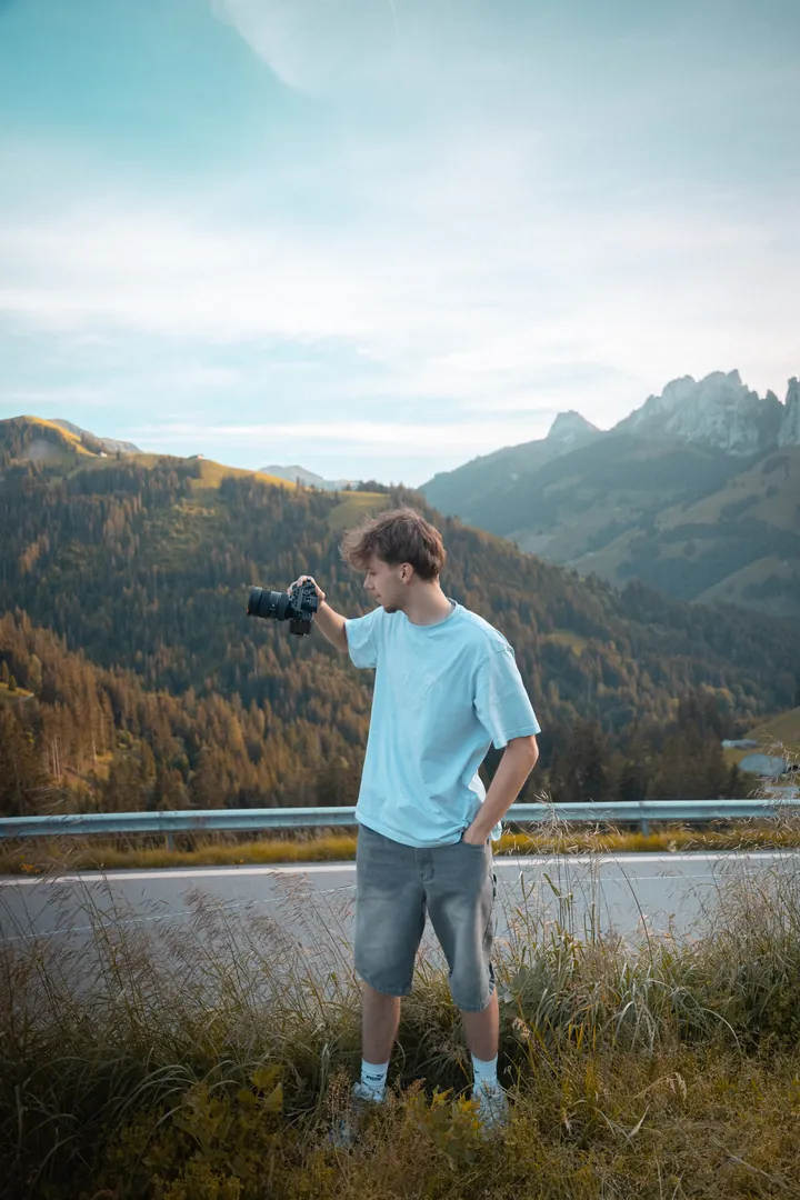 Gabriel Schertenleib, appareil photo à la main, au bord d'une route de col face aux Gastlosen