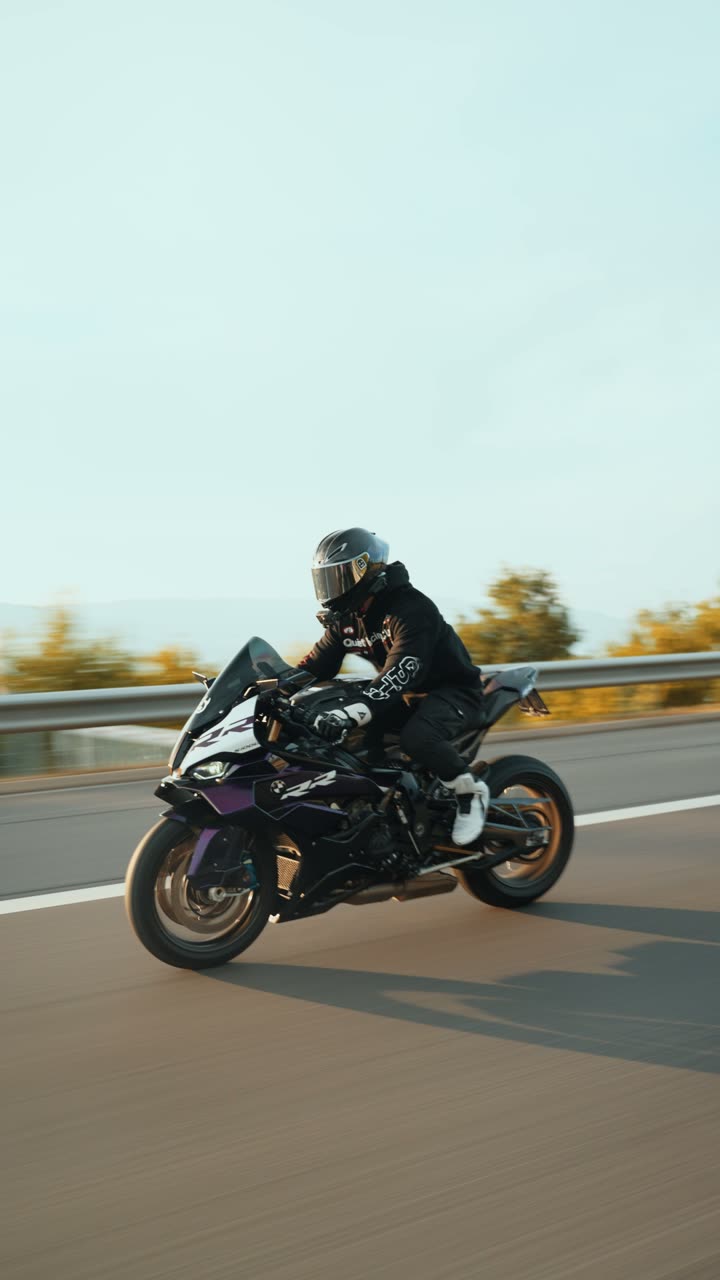 Motard en mouvement sur une route de campagne, filmé depuis un véhicule roulant à sa hauteur.